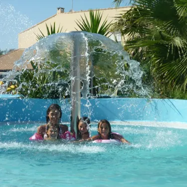 Camping La Plage et le Bord de Mer : enfants souriants sous une fontaine d'eau.