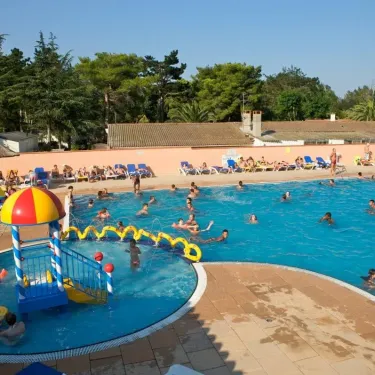 Camping Le Littoral : enfants jouent à l'eau près d'une structure ludique colorée dans la piscine.