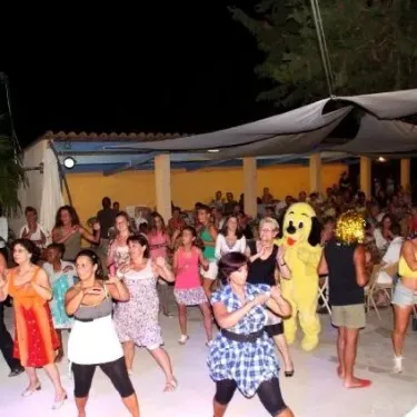 Soirée dansante au Camping La Barque : groupe de femmes danseant avec un personnage costumé.