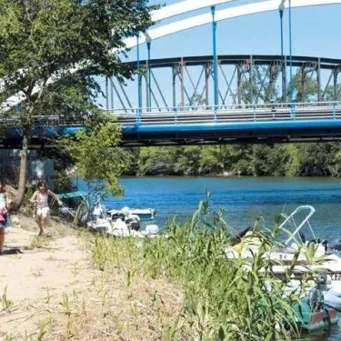 Deux enfants courant près d'un pont bleu au bord d'une rivière, Camping La Barque.