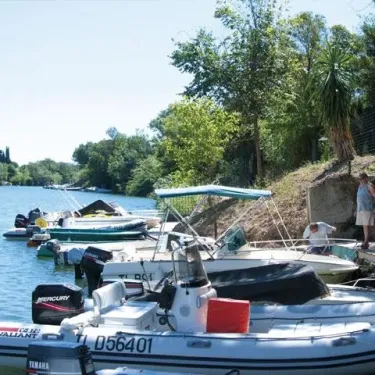 Bateaux de plaisance amarrés le long d'une rive verdoyante, Camping La Barque.