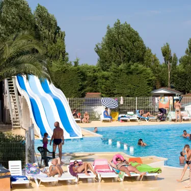 Camping L'Europe avec toboggan bleu et personnes détendues autour de la piscine
