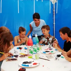 Enfants peignant avec des pots de peinture Prime Click dans une tente bleue au Camping La Côte Sauvage.
