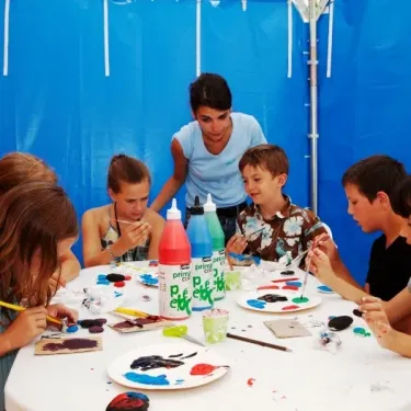Enfants peignant avec des pots de peinture Prime Click dans une tente bleue au Camping La Côte Sauvage.