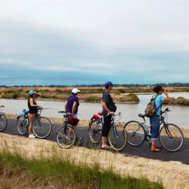 Camping La Côte Sauvage : groupe de personnes à vélo sur un chemin près d'un étang.