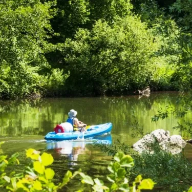 Personne en kayak sur une rivière entourée de forêt dense, Camping La Boissière