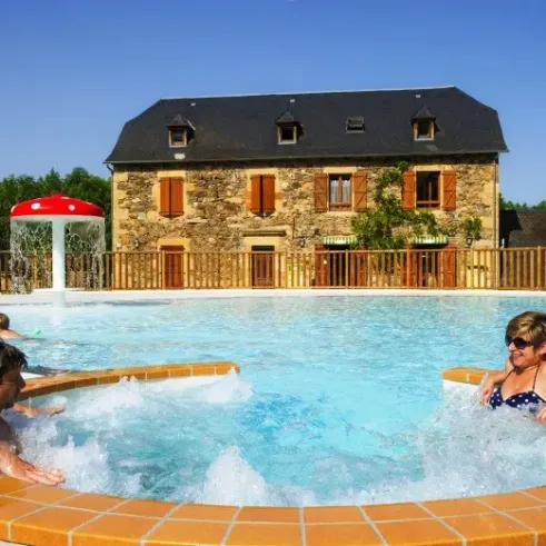 Camping La Boissière : piscine chauffée avec une maison traditionnelle en arrière-plan