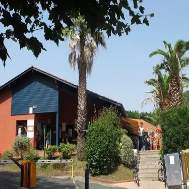 Photo camping Bela Basque avec palmiers et bâtiment bleu