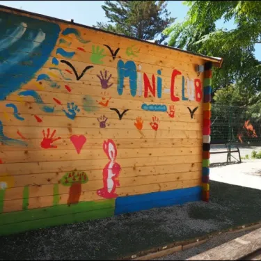 Mur décoratif avec le logo Mini Club au Camping Le Soleil Bleu