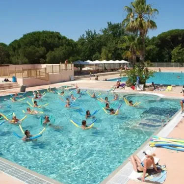 Camping Oasis Village : groupe faisant de l'exercice aquatique dans la piscine avec des bâtonnets flottants.