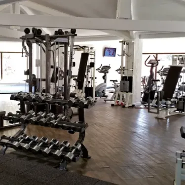 Camping Oasis Village : salle de sport équipée avec machines de musculation et barres de poids.