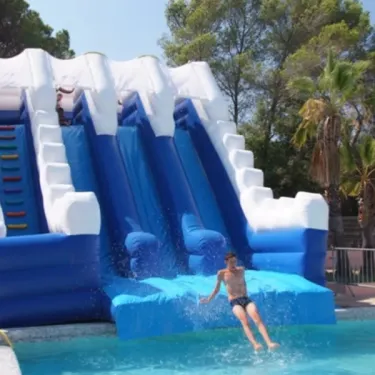 Glisseur gonflable bleu et blanc au Camping Oasis Village, enfants qui descendent dans la piscine.