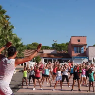 Camping Oasis Village : groupe faisant du fitness sur le terrain, entraînement collectif sous un ciel bleu.