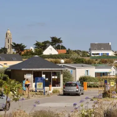 Vue du camping Les Paludiers avec une tour et des cabanes mobiles au premier plan.