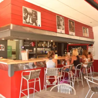 Bar rouge du Camping Les Paludiers avec clients assis à la barre