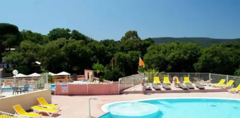 Piscine avec chaises longues jaunes et vue sur les arbres au Camping Parc Montana