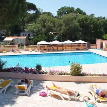 Camping Parc Montana : piscine entourée de transats et d'ombrelles sous un ciel bleu.