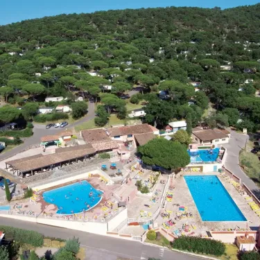 Camping Parc Montana : vue aérienne du parc avec piscines, cabanes et forêt.