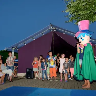 Personnage costumé présente une performance devant les enfants au Camping Les Ilates