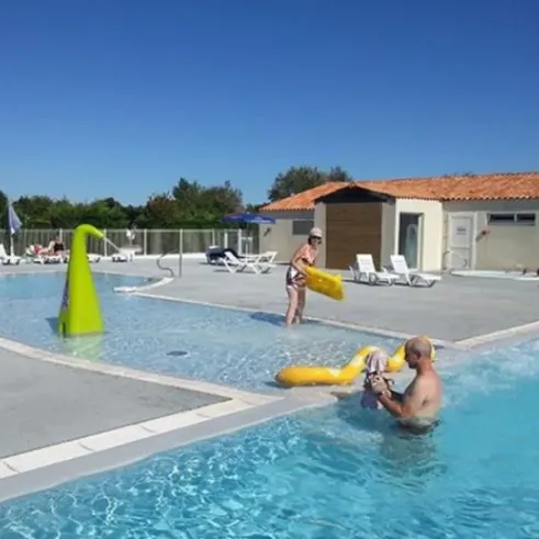 Piscine extérieure avec enfants jouant autour d'un toboggan coloré et d'une structure en forme de champignon