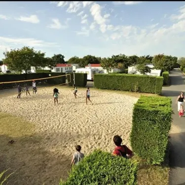Enfants jouant au volley-ball sur terrain de sable Camping Les Ilates