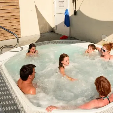 Camping Les Ilates : famille profitant d'une baignade relaxante dans un jacuzzi extérieur