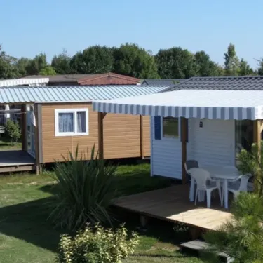 Mobile home avec auvent rayé et table de jardin dans le camping Résidence du Lac