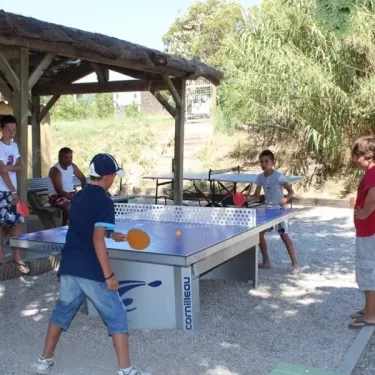 Enfants jouant au ping-pong sous une pergola à Camping Beau Rivage