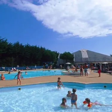 Enfants qui jouent dans la piscine du Camping Bois d'Amour sous un ciel bleu.