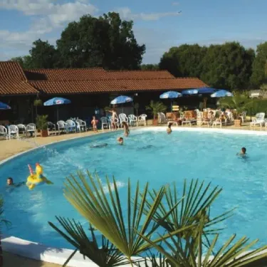 Personnes nageant dans la piscine du Camping Les Cigales sous un ciel bleu