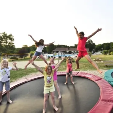 Photo camping Les Cigales : enfants sautent sur trampoline