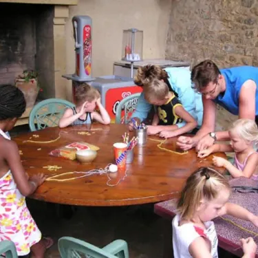 Enfants qui font une activité manuelle autour d'une table au Camping Le Céou