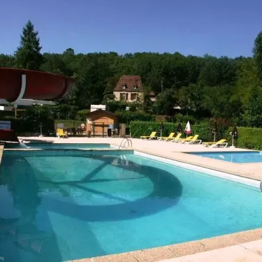 Piscine avec toboggan et chaises longues au Camping Le Céou