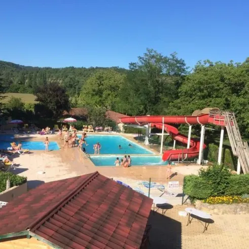 Piscine avec toboggan rouge et enfants autour au Camping Le Céou