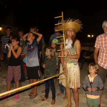 Fête nocturne au Camping Le Céou avec enfants en tenue hawaïenne et lumières douces.