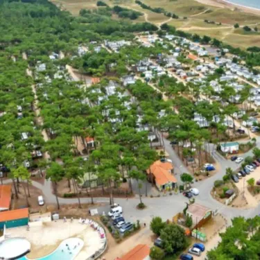 Vue aérienne du Camping La Plage de Riez avec des caravanes, voies de circulation, piscine et zones arborées.