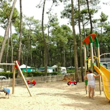 Enfants jouent sur une aire de jeux avec balançoire et toboggan au Camping La Plage de Riez.