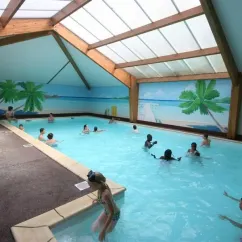 Piscine couverte avec murs décorés de palmiers, enfants nageant à Camping La Grand Métairie