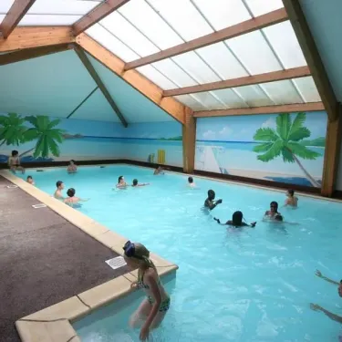 Piscine couverte avec murs décorés de palmiers, enfants nageant à Camping La Grand Métairie