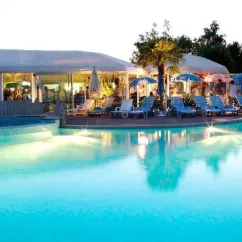 Piscine extérieure au coucher du soleil avec chaises longues et parasols, Camping La Grand Métairie