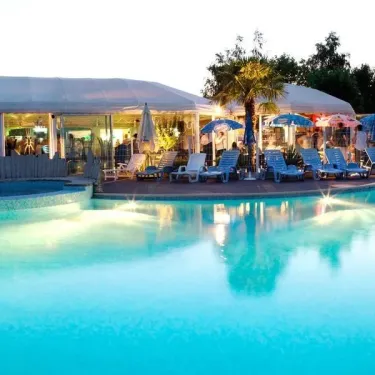 Piscine extérieure au coucher du soleil avec chaises longues et parasols, Camping La Grand Métairie