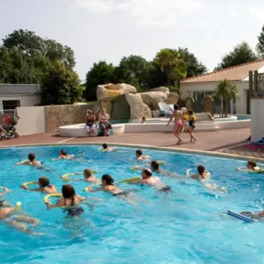 Groupes d'enfants nageant avec flotteurs dans une piscine extérieure, Camping La Grand Métairie