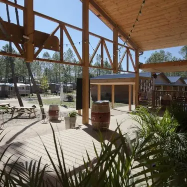 Terrasse en bois avec tonneaux décoratifs et mobilier extérieur dans le camping Fram Nature.