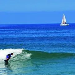 Surfeur sur une vague, voilier à l'horizon, Camping Azu'Rivage