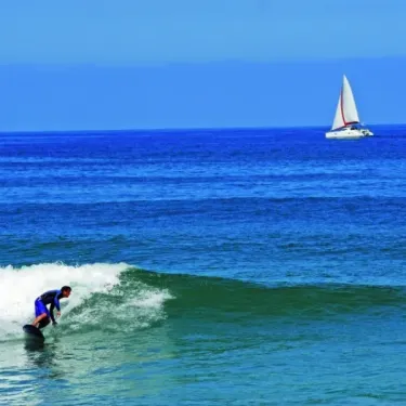 Surfeur sur une vague, voilier à l'horizon, Camping Azu'Rivage