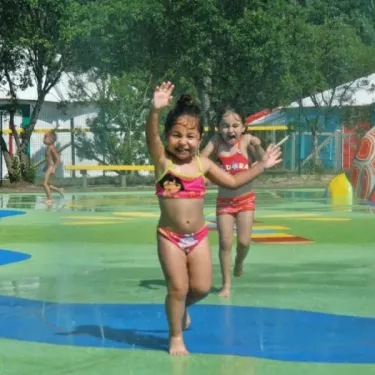 Deux enfants qui courrent dans une zone de jeux aquatique au Camping Le Col Vert.