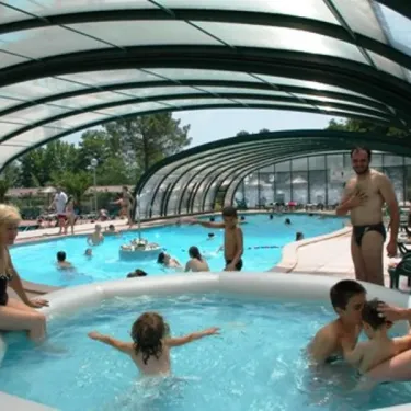 Famille qui se détend dans une piscine couverte au Camping Le Col Vert.
