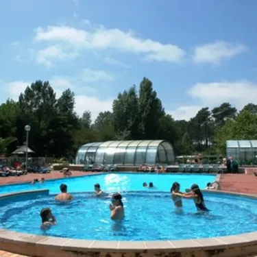 一群人 nageant dans une grande piscine extérieure au Camping Le Col Vert.