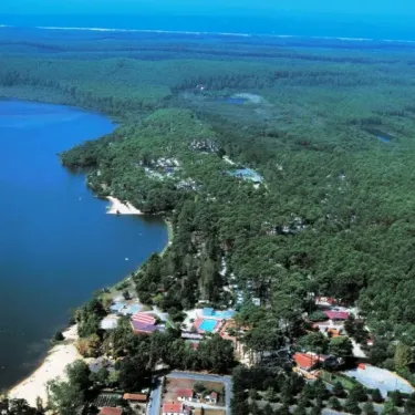 Vue aérienne du camping entouré de forêt et d'un lac, Camping Le Col Vert