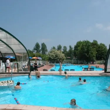 Piscine couverte du Camping Le Col Vert avec des enfants nageant et des adultes se détendant.